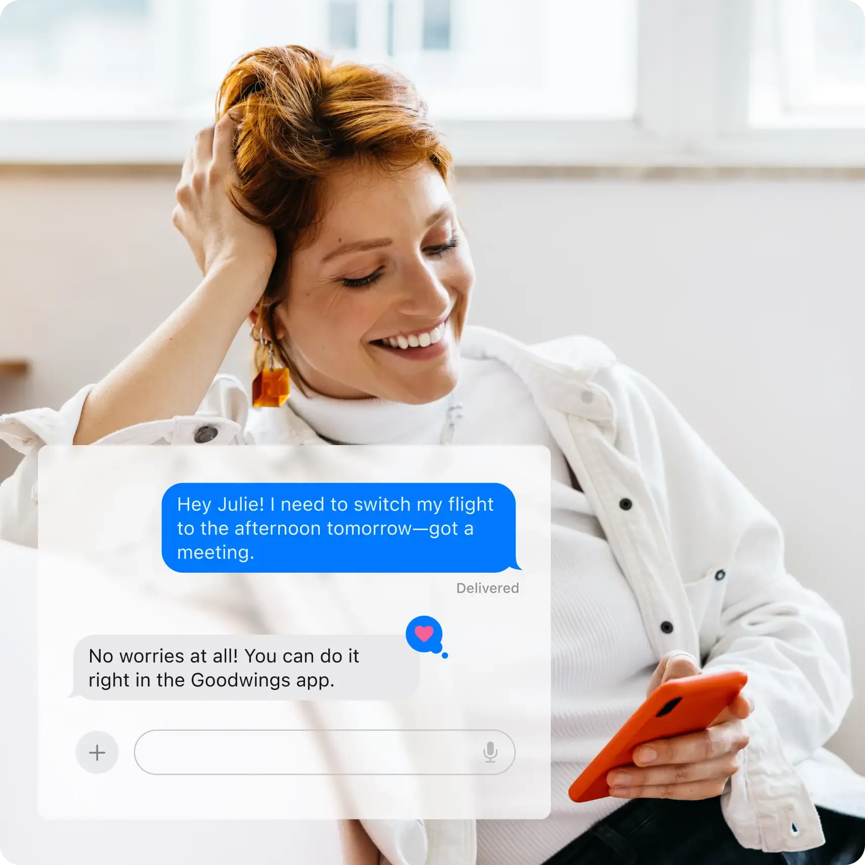 Woman smiling while using smartphone showing flight change conversation in Goodwings app